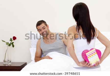 Wife giving her husband  a valentine\'s present in bed