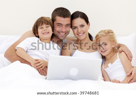 Parents and children using a laptop in bed