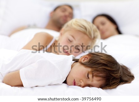 Children sleeping with his parents in a big bed