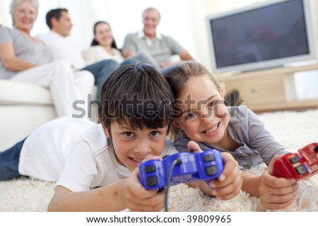 Children playing video games on floor and family sitting on sofa