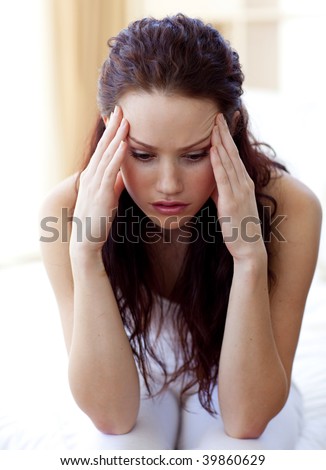 Beautiful girl having a headache sitting in bed