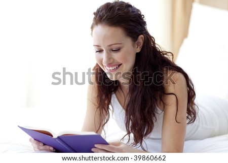 Beautiful smiling woman reading a book in bed