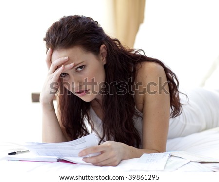 Beautiful woman in bed getting frustrated with bills to pay