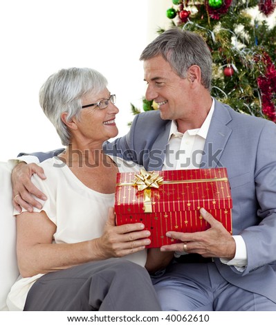 Senior man giving a Christmas present to his wife at home