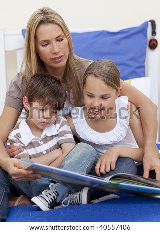 Mother reading a book with her children in bedroom