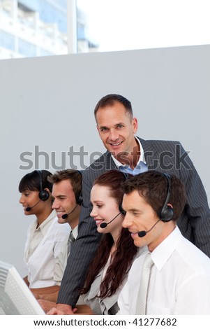Smiling manager working with his team in a call center