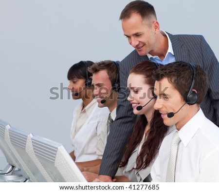 Attractive manager checking his young team work in a call center