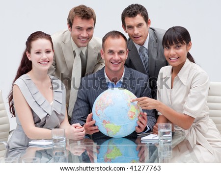 Smiling business team holding a terrestrial globe in the office