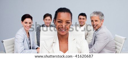 Afro-American businesswoman smiling in a meeting with her colleagues working in the background