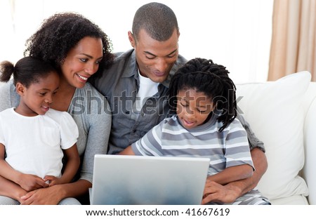 Happy Afro-American family using a laptop on the sofa