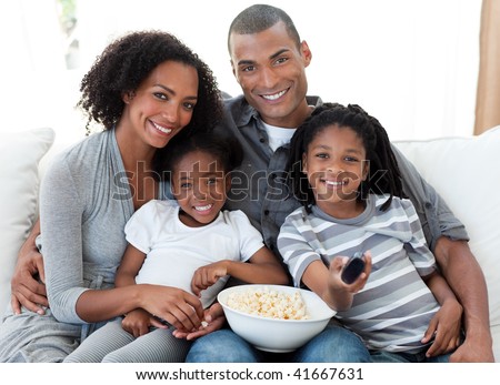 Afro-American family watching television and eating popcorn at home