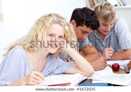 Happy teen girl studying in the library with her friends. Concept of education