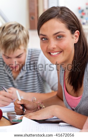 Smiling teen girl studying in the library with her friends. Concept of education