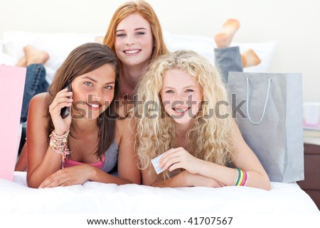 Happy teen girls lying on bed after shopping clothes