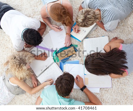 High angle of teenagers lying on the ground studying together