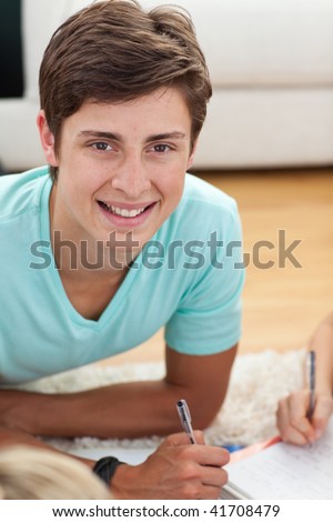 Portrait of a teen guy doing homework on the floor
