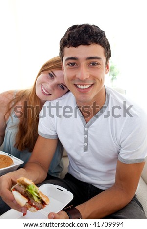 Teenagers eating burgers and fries on the sofa