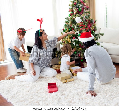 Family decorating a Christmas tree at home