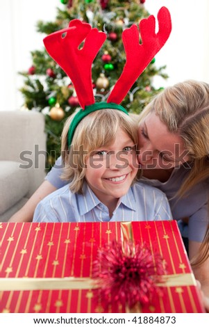 Loving mother kisses son at Christmas and sitting on the floor