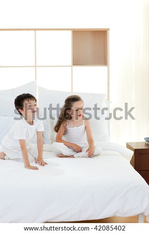 Smiling Brother and sister having fun in parent\'s bedroom