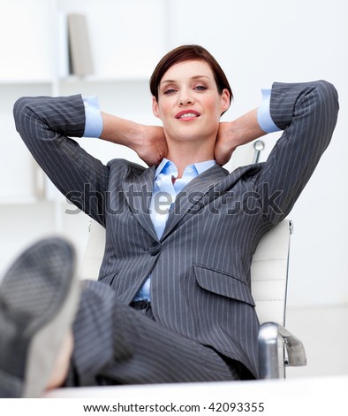 Smiling businesswoman leaning back on a chair with his feet on the desk in the office