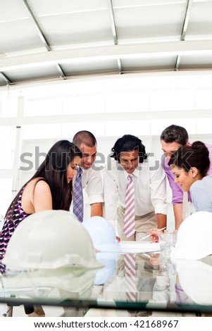 International engineers and their manager discussing blueprints in a meeting