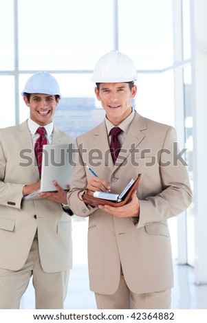 Portrait of two architects wearing hard hat smiling at the camera