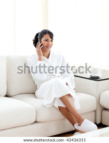 Young woman on phone sitting on the sofa at home