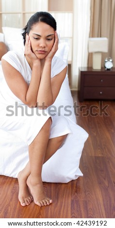 Young woman having a headache sitting on the bed