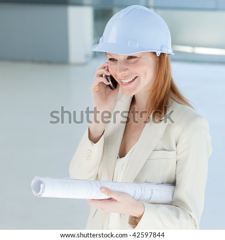 Young female engineer on phone carrying blueprints
