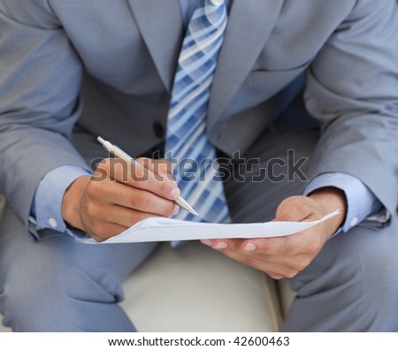 Close-up of a businessman sitting and writing on a paper