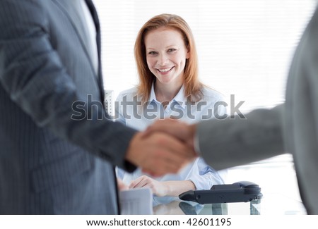 Businesswoman smiling with businessmen greeting each other in the foreground at a job interview