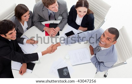 Business people smiling at the camera while closing a deal in a meeting