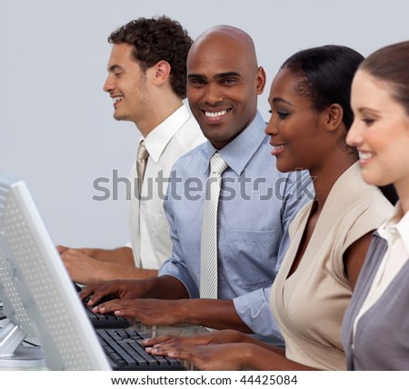 Ethnic businessman sitting in a row with his team smiling at the camera
