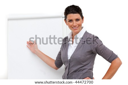 Confident female executive pointing at a board against a white background