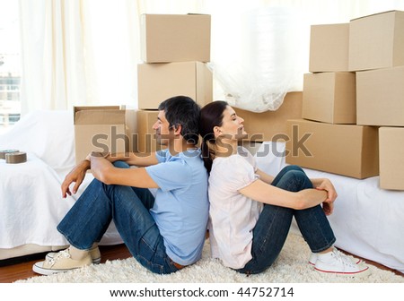 Tired couple relaxing sitting on the floor while moving house
