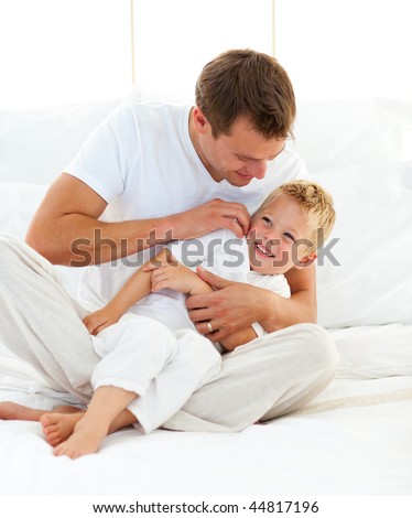 Animated little boy having fun with his dad on a bed