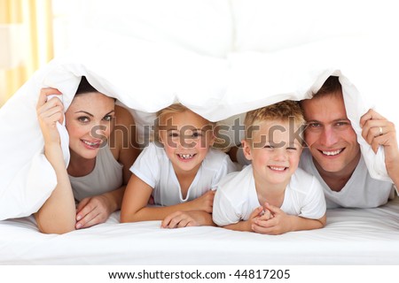 stock photo : Happy family playing together on a bed at home
