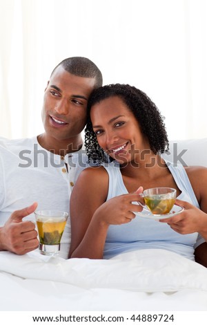 Intimate couple drinking a cup of tea on their bed. Concept of love.