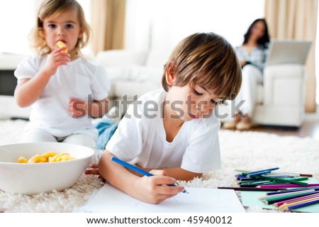 Cute little gir eating chips and her brother drawing in the living-room