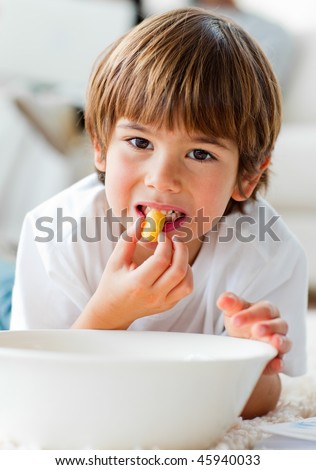 Cute little boy eating chips lying on the floor in the living-room