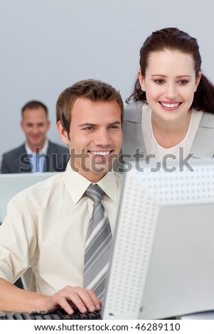 Smiling business partners working together at a computer in the office