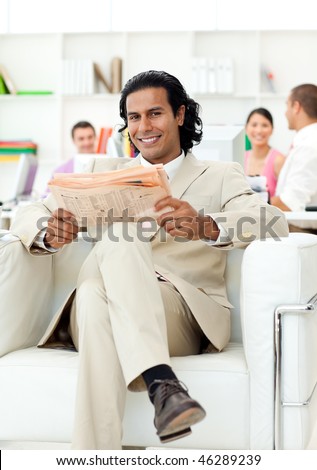 Self-assured manager reading a newspaper in the office