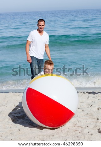 Animated father and his son playing with a ball at the beach