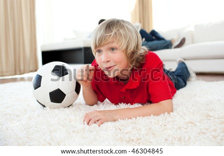 Excited boy watching football match lying on the floor in the living-room