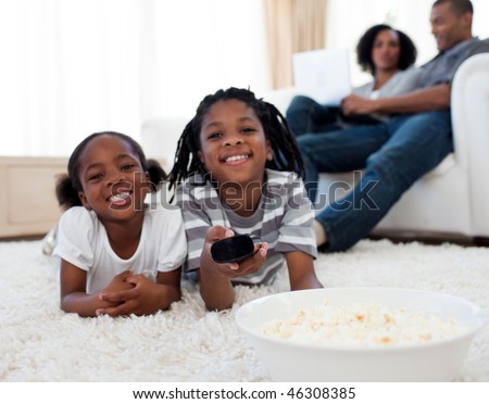 Little siblings watching television and eating pop corn in the living room