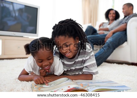 Concentrated children reading a book lying on the floor