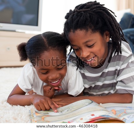 Pensive children reading a book lying on the floor