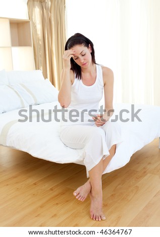 Disappointed woman finding out pregnancy test sitting on her bed