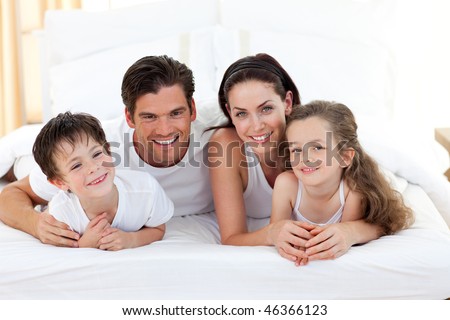 Smiling family having fun lying on the bed